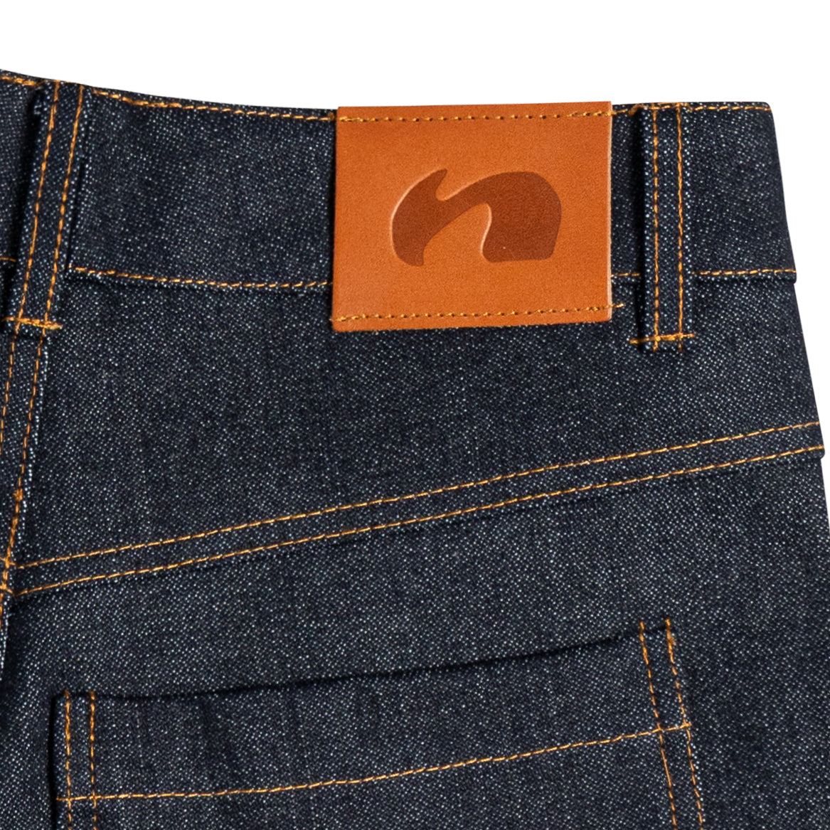 Close-up of dark indigo, raw denim shorts showing the waistband and a brown leather patch label with embossed neuricos logo.
