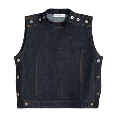 A sleeveless dark indigo, raw denim vest with silver metal donnut buttons on the shoulders, sides, and hem, displayed flat against a solid white background. 